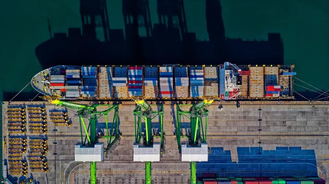 Kapal kontainer bersandar di dermaga dengan derek pelabuhan, dilihat dari udara
